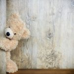 miś skrada się za drewnianych drzwi