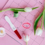 Kalendarz z zaznaczoną datą zapłodnienia, test ciążowy, kwiaty i smoczek